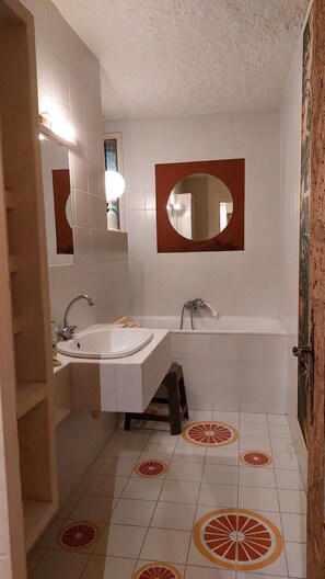 A bathroom with a white sink, a bathtub, and a mirror.
