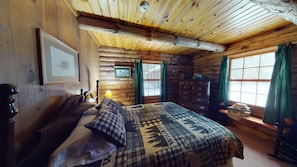 A rustic wooden room with a bed, dresser, and a window with curtains.
