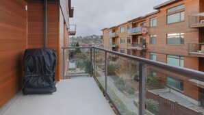 A balcony with a covered grill, a metal railing, and a view of adjacent buildings. - Mt. Tolmie View-Spacious, Bright NE Facing Two Bedroom Condo with Den by Victoria Prime! (Victoria)