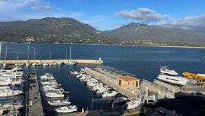 A marina with boats docked, a small building, and a mountainous backdrop. - Apartment-Propriano (Propriano)