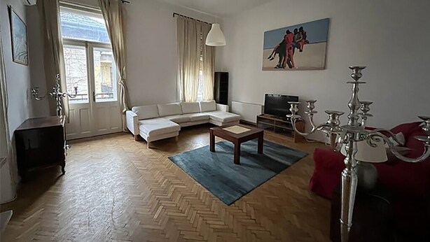 Ein Wohnzimmer mit einer Couch, einem Couchtisch, einem Fernseher und einer Chandelüster.