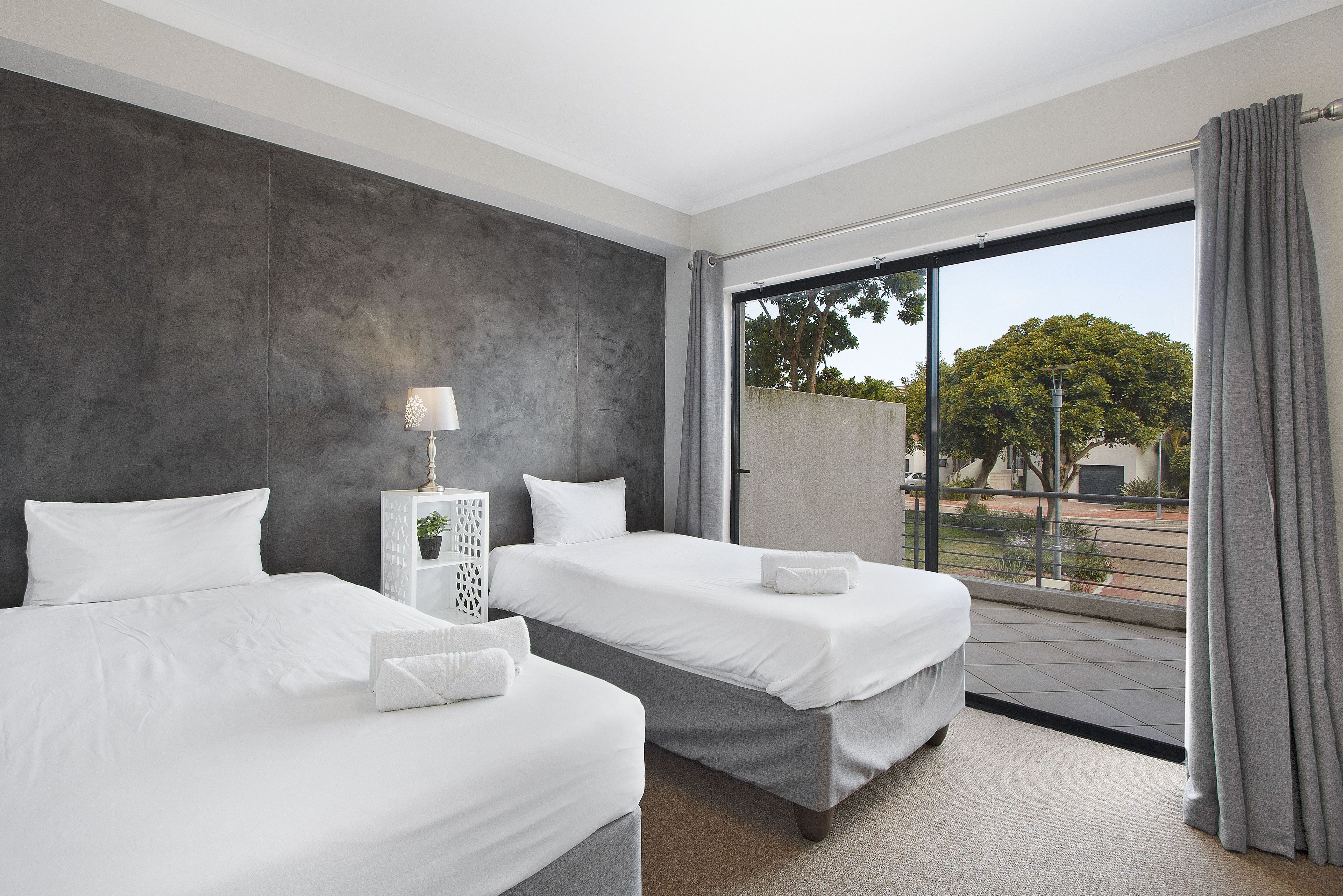 A hotel room with two beds, a large window, and a view of the outdoors.
