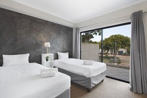 A hotel room with two beds, a large window with a view of the outdoors, and a grey accent wall. - Waterstone East C103 (Cape Town)