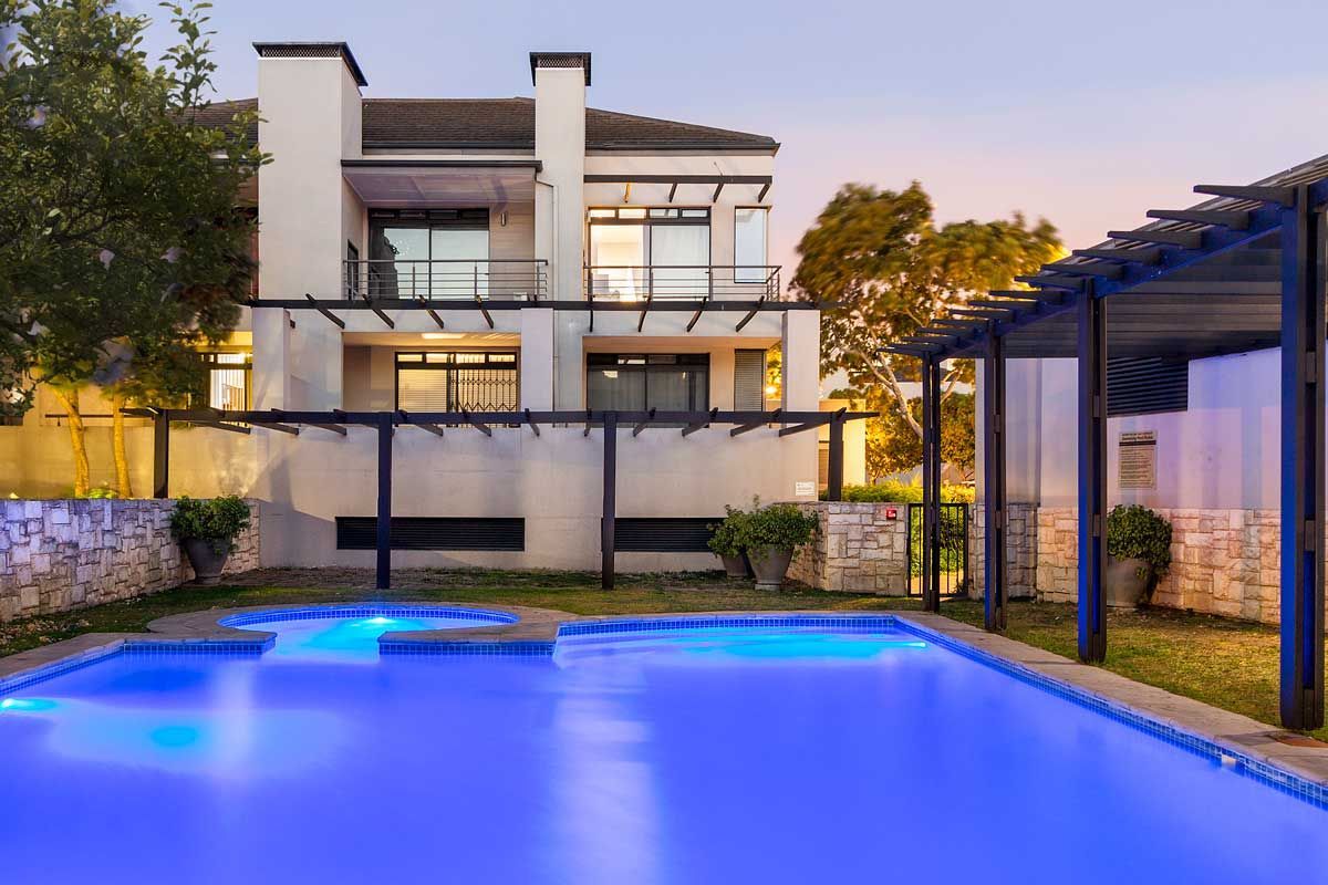 A modern two-story building with a swimming pool in front.