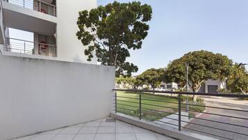 Un bâtiment moderne à la façade plate, doté d’un balcon carrelé et d’une rambarde en métal.