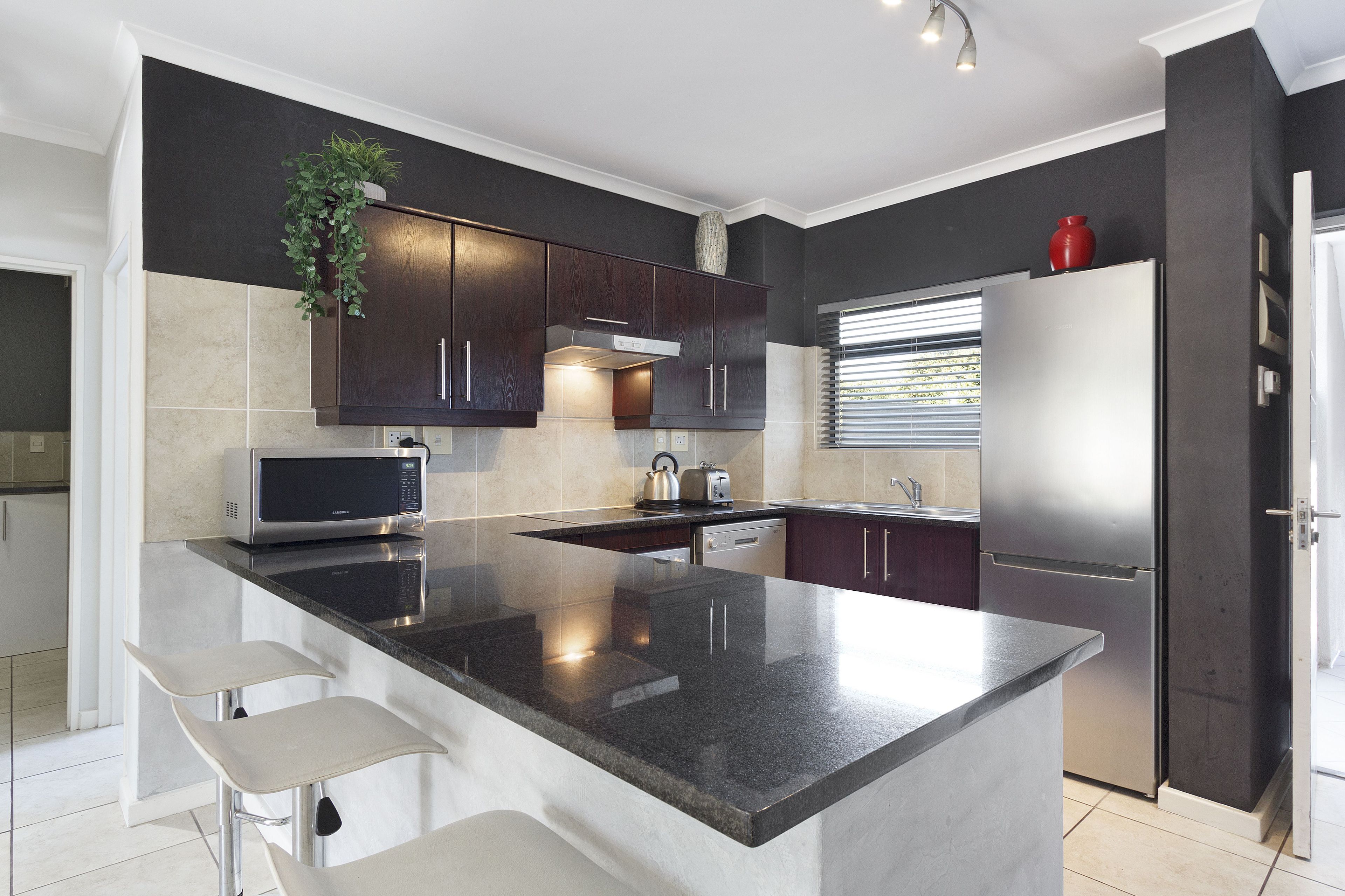 A modern kitchen with a central island, stainless steel appliances, and dark cabinetry.