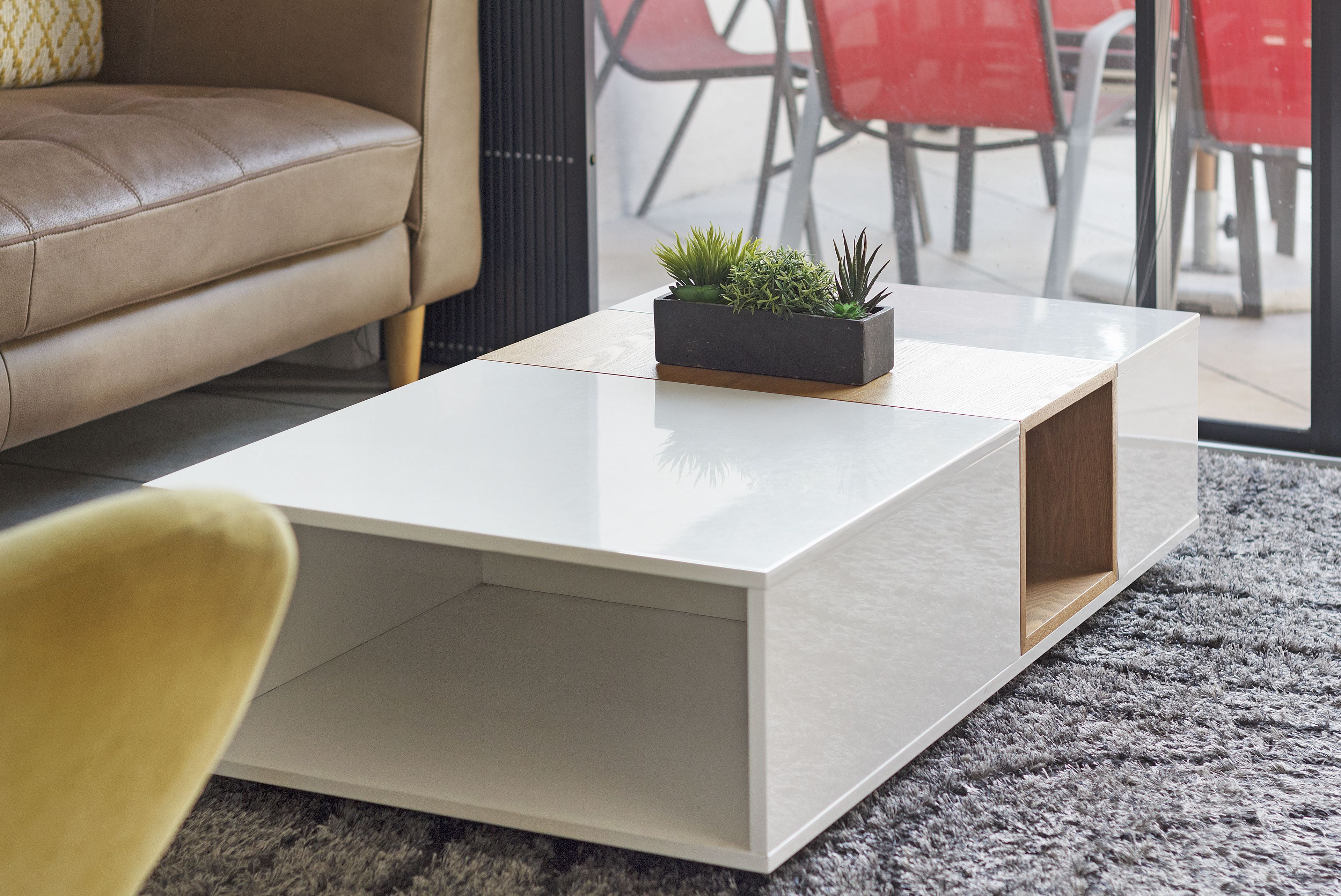 Un salon moderne avec une table basse blanche, un canapé et un fauteuil rouge.
