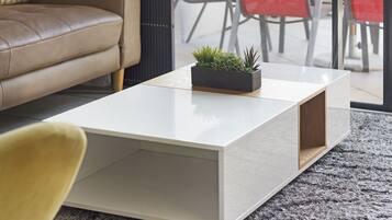 Un salon moderne avec une table basse blanche, un canapé et un fauteuil rouge.
