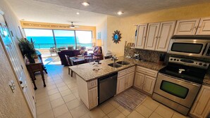 A kitchen with a view of the ocean, a dining area with a view, and a ceiling fan. - Sonoran Spa E603 - 2 BR Next to the Pool, High Speed Wi-Fi - Beachfront Upper Floor Luxury Condo (Puerto Peñasco)
