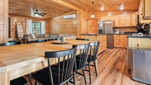 A wooden cabin interior with a dining area, kitchen, and a sofa in the living room.