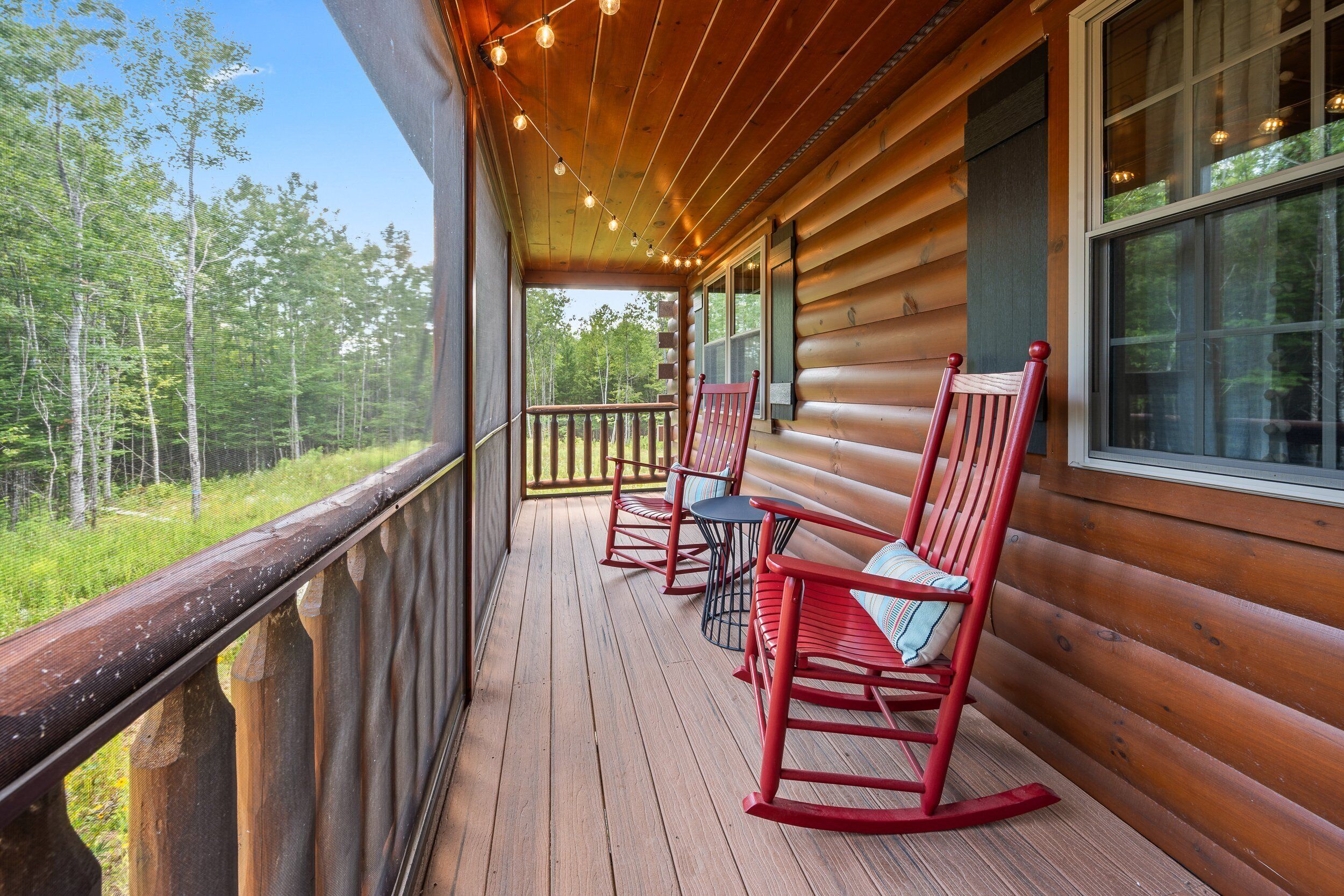 A wooden cabin with a porch featuring rocking chairs and a small table.