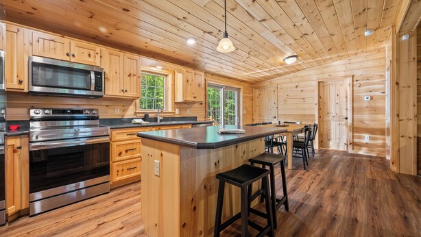 A modern kitchen with wooden cabinetry, stainless steel appliances, and a central island with bar stools.