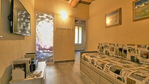 Una stanza con un letto ricoperto da una coperta a fantasia, una TV a schermo piatto montata a parete e un soffitto in legno.