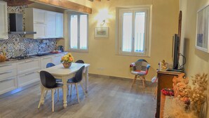 Una cucina con mobili bianchi, un tavolo da pranzo con sedie e un soffitto in legno.