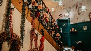 A staircase with floral decorations, a wooden handrail, and a green door in the background. - Le Nid I  Charming one-roomed flat (Guebwiller)