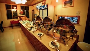 A buffet setup with multiple serving stations, a red table, and a large window. - Captal Island Villa (Mathiveri)