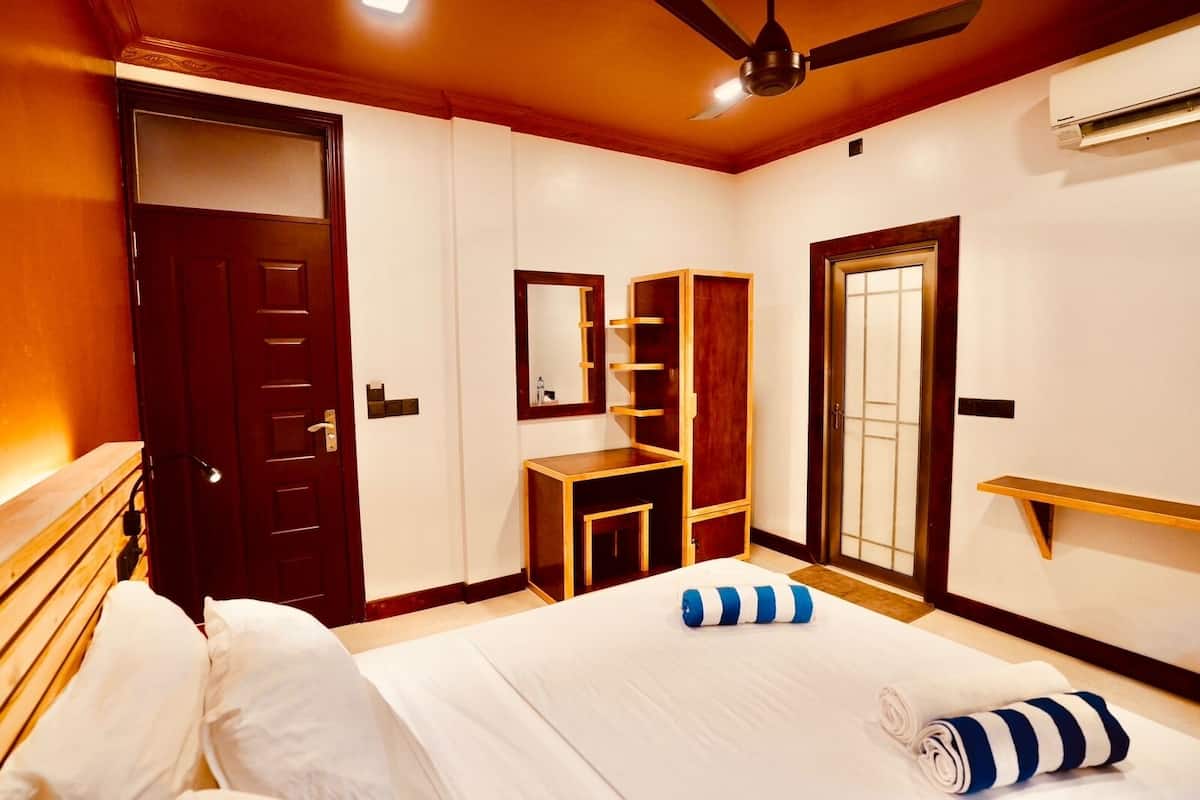 Una habitación de hotel con cama, armario, espejo y ventilador de techo.