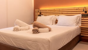 A neatly made bed with white and beige towels, a wooden headboard, and a wall-mounted light fixture. - Captal Island Villa (Mathiveri)