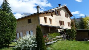 Una casa de dos pisos con techo inclinado, chimenea y porche delantero.
