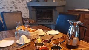 A wooden dining table set with breakfast items, including bread, butter, jam, and coffee.