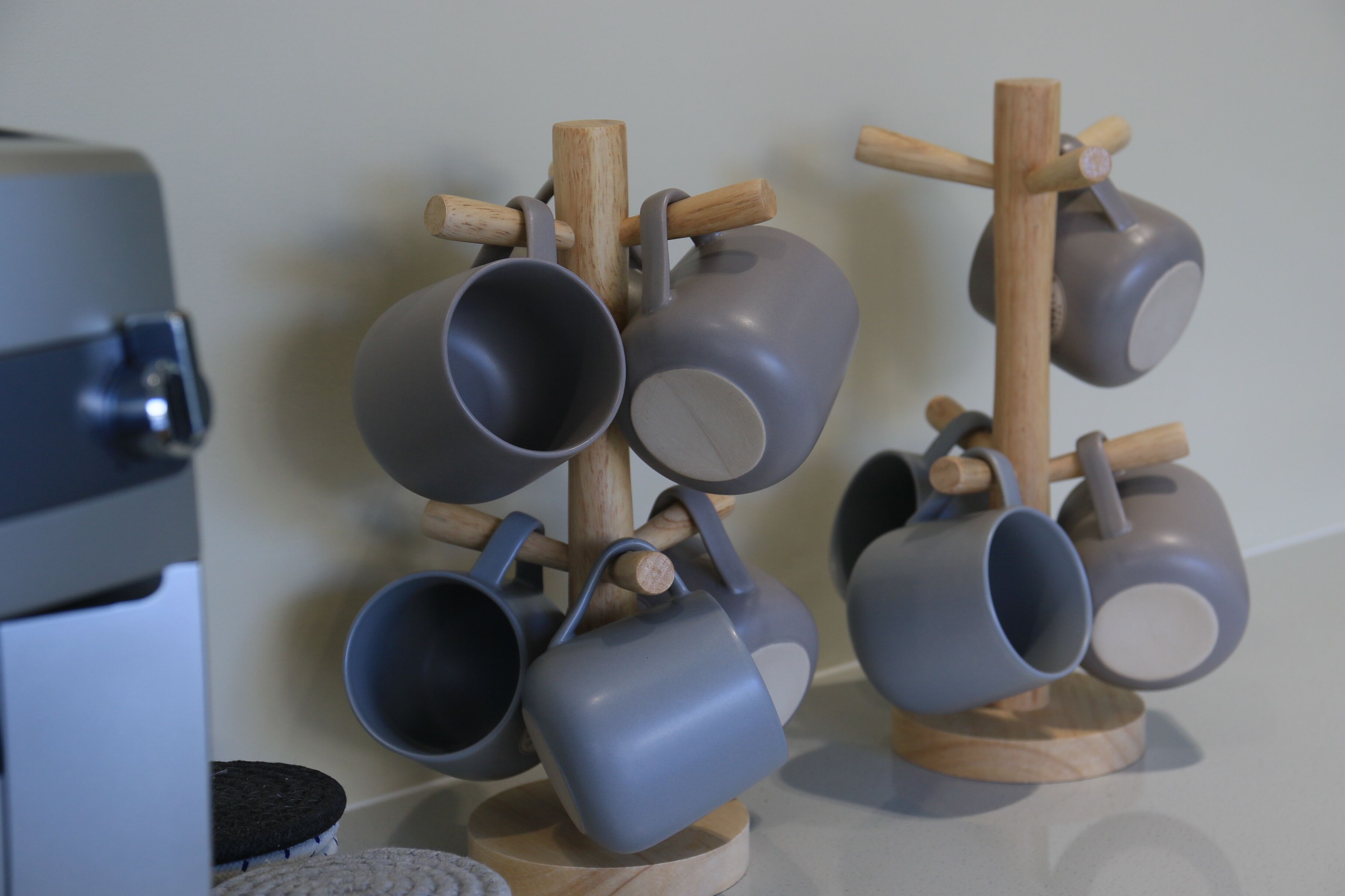 A wall-mounted rack holding multiple gray mugs.