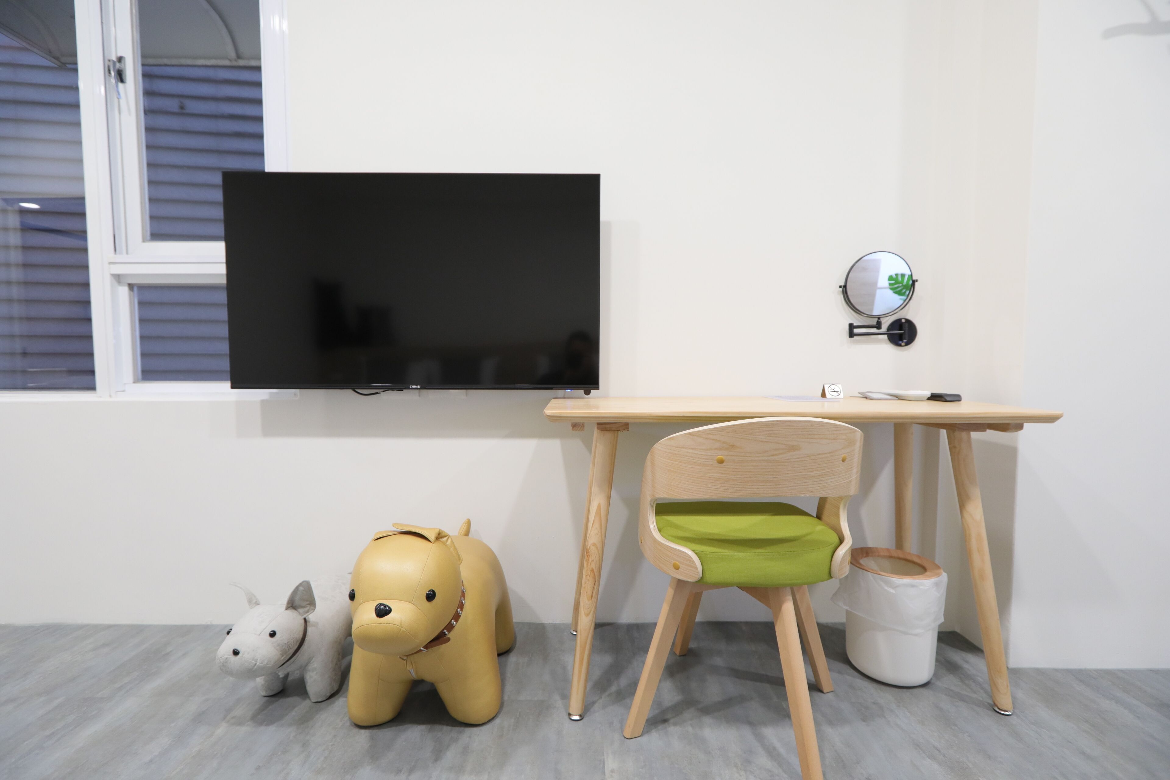 Une chambre d’enfant avec une télévision, un bureau en bois, une chaise et deux peluches.