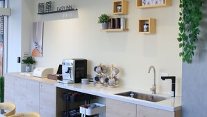 A modern kitchen with a built-in coffee machine, wooden cabinets, and a hanging light fixture. - EasyInn (Yuchi)