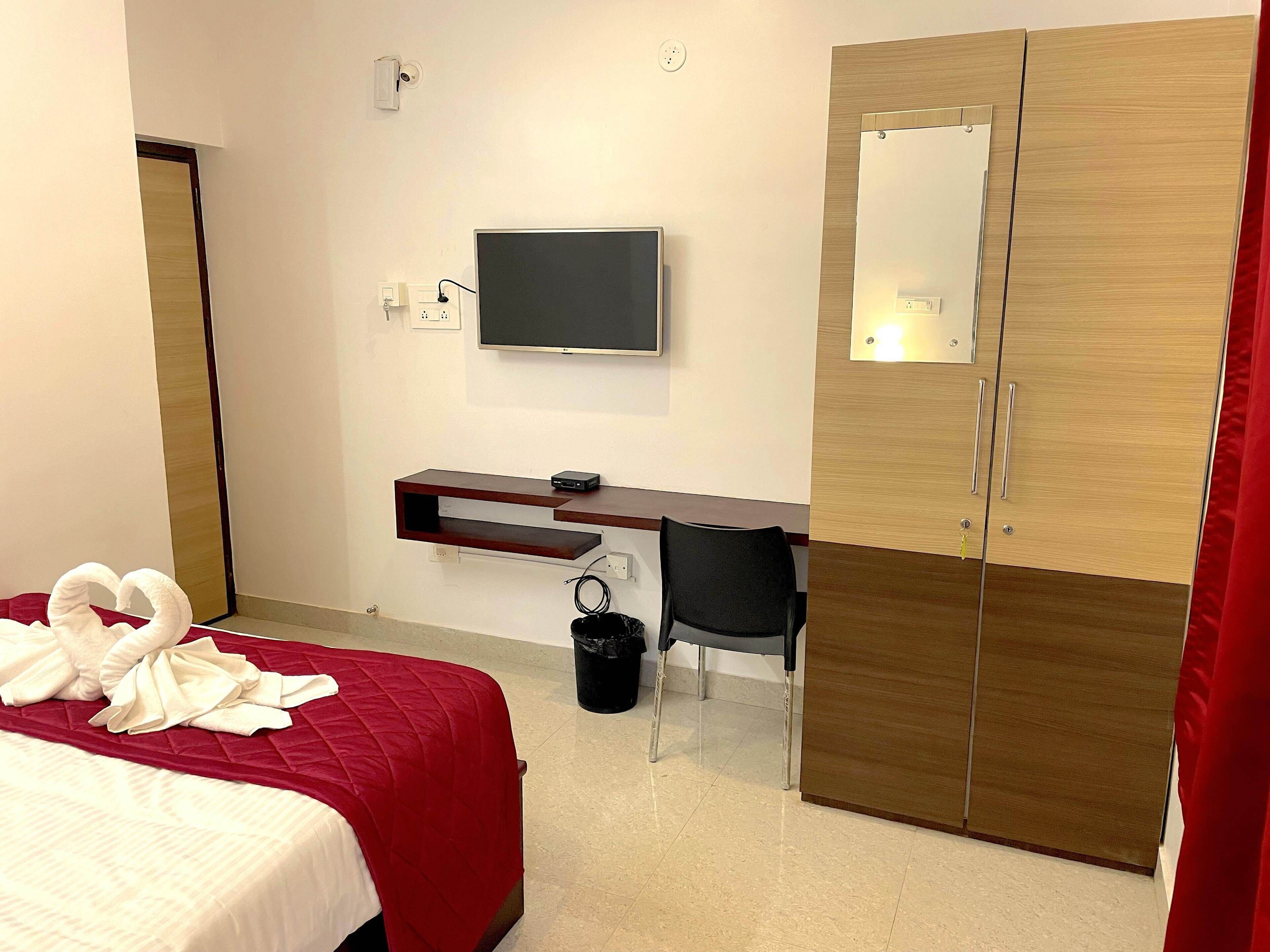 Una habitación de hotel con cama, escritorio, televisor y armario.