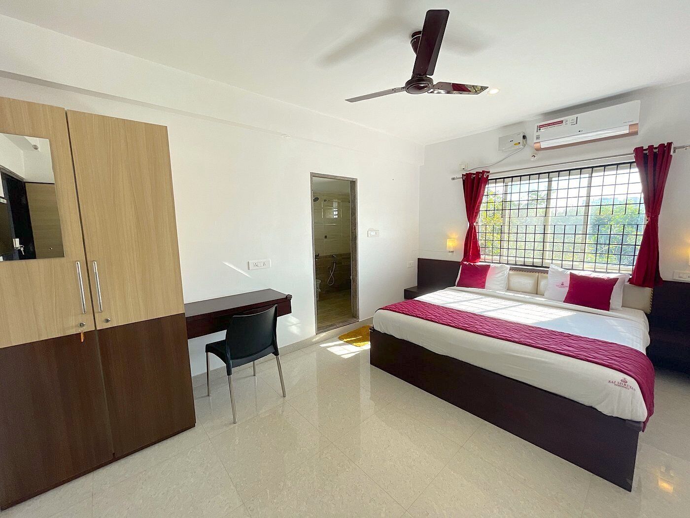 A modern hotel room with a bed, a desk, a wardrobe, and a ceiling fan.