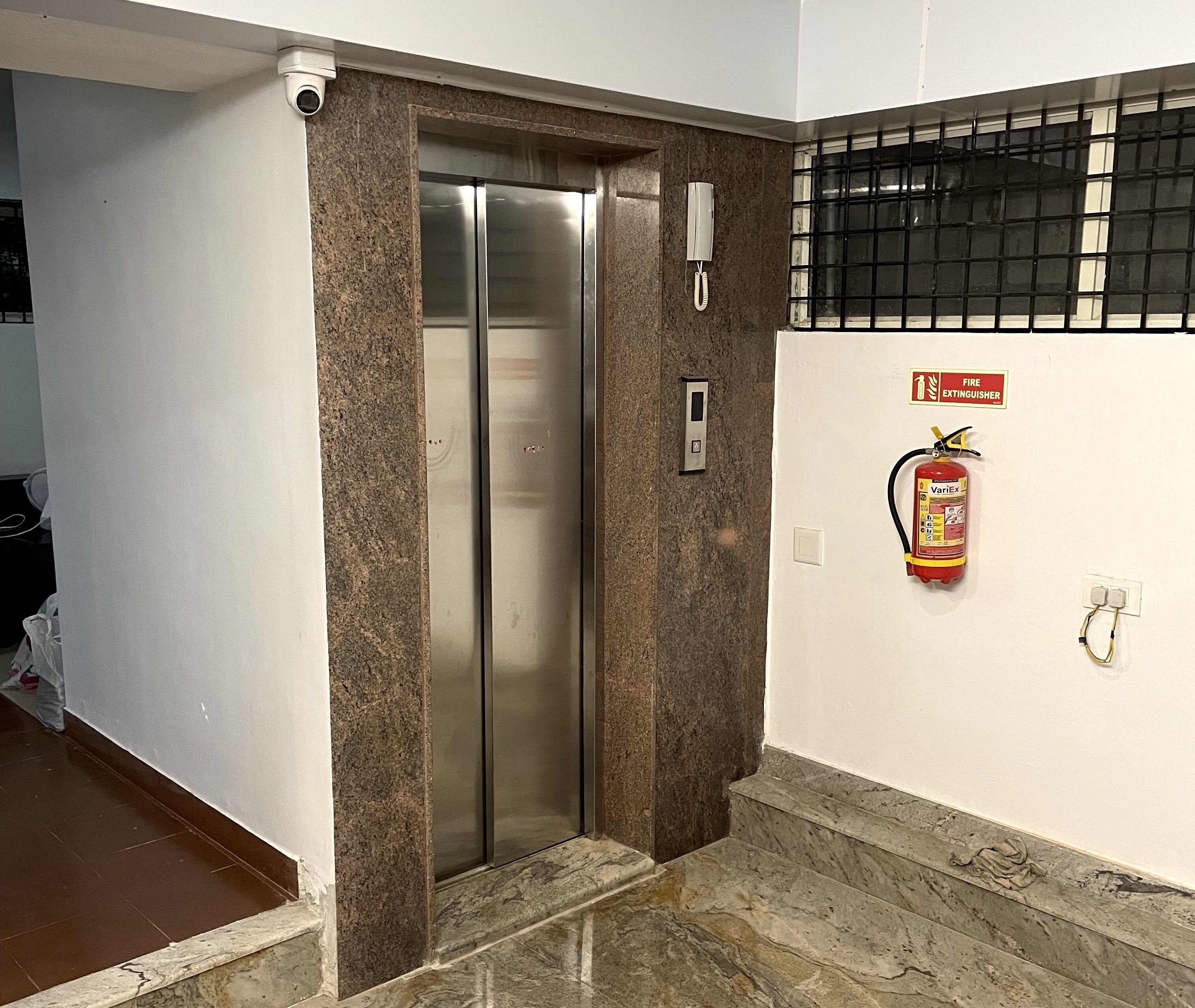 An elevator with a fire extinguisher mounted on the wall beside it.