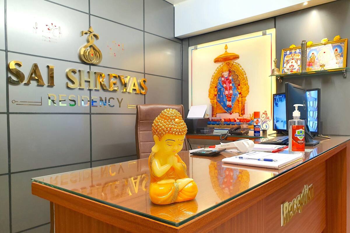 A reception desk with a Buddha statue, a computer, a phone, and a hand sanitizer bottle.