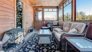 A wooden cabin with a covered porch, wicker furniture, and a view of the mountains. - Spruce Cliffs at Timber Creek (Bethel)