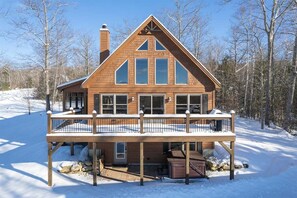 Eine zweistöckige Holzblockhütte mit Balkon, umgeben von Schnee und Bäumen.