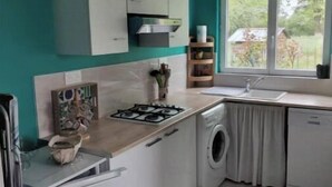 Une cuisine compacte équipée d’un lave-linge, d’une cuisinière et d’une fenêtre donnant sur un espace verdoyant.