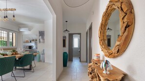 Une cuisine spacieuse avec un coin repas, comprenant une table en bois, des chaises vertes et un grand miroir au mur.