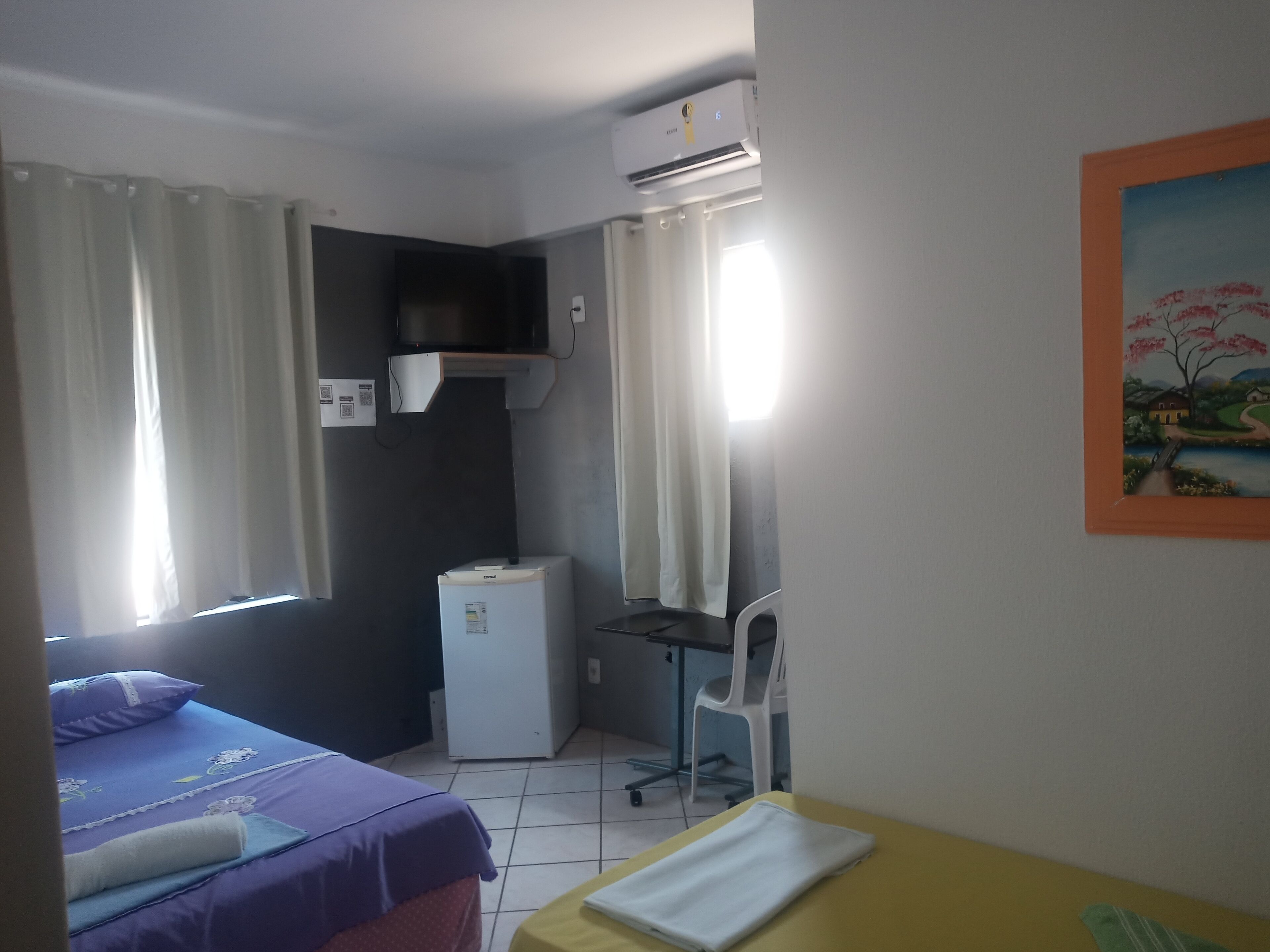 Una habitación con una cama, un escritorio, una silla y un refrigerador pequeño.