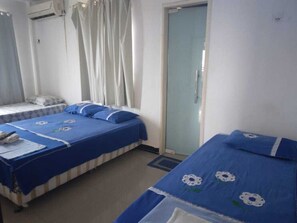 Una habitación con dos camas, una ventana con cortinas, un equipo de aire acondicionado y una puerta.