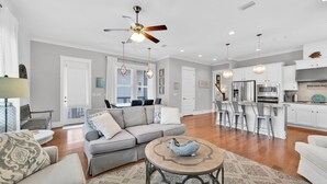 A spacious living room with a grey sofa, a round coffee table, and a ceiling fan. - Luna de Soleil ~ Free Golf Cart and No Pet Fees ~ Near Beach & Pool (Santa Rosa Beach)