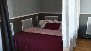 A bedroom with a bed, a curtain, and wooden flooring. - Andrea apartment (Fontenay-sous-Bois)
