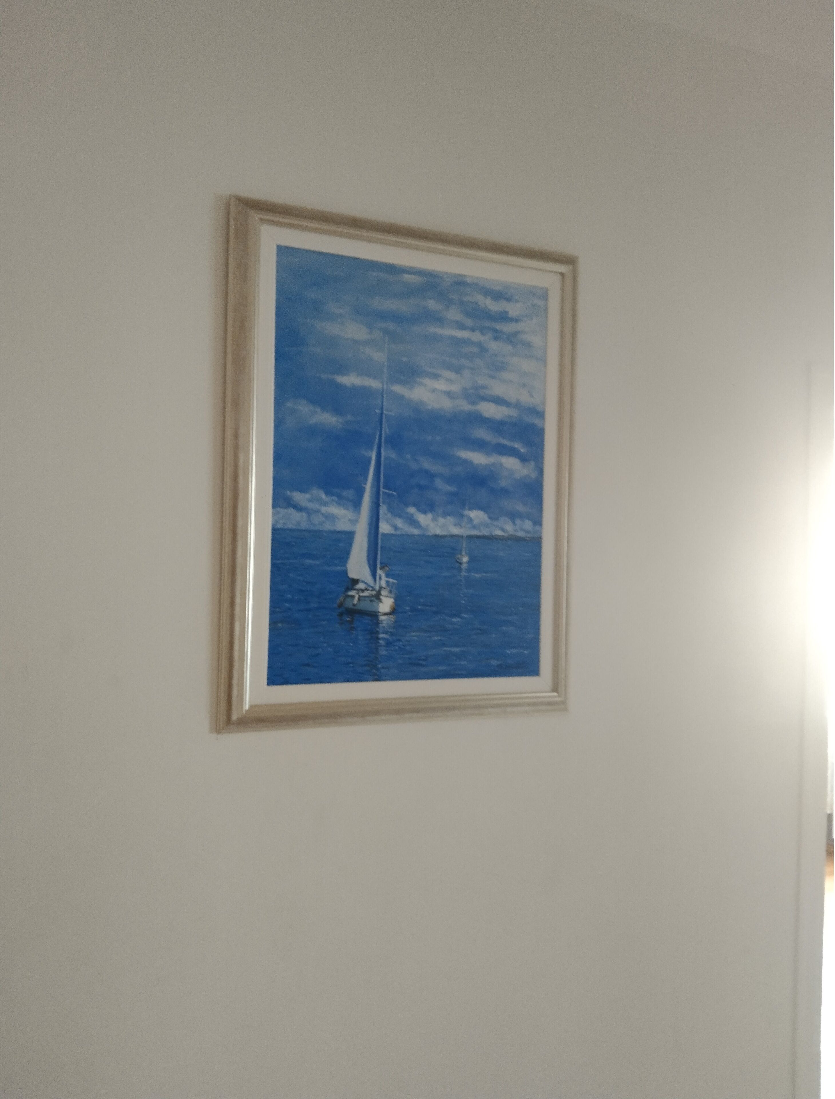 A framed painting of a sailboat on the water.