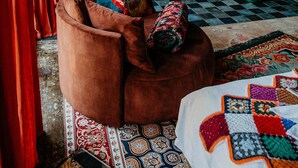A rustic bathroom with a freestanding bathtub, a wooden bench with cushions, and a patterned rug. - "La Bohème" Chic & Unique Designer Loft in Alsace (Guebwiller)