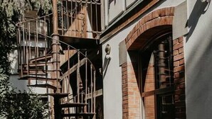 A building with a brick facade, a wooden staircase, and a cactus plant.