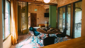 A cozy room with a wooden ceiling, a round table with chairs, and a zebra-patterned door.