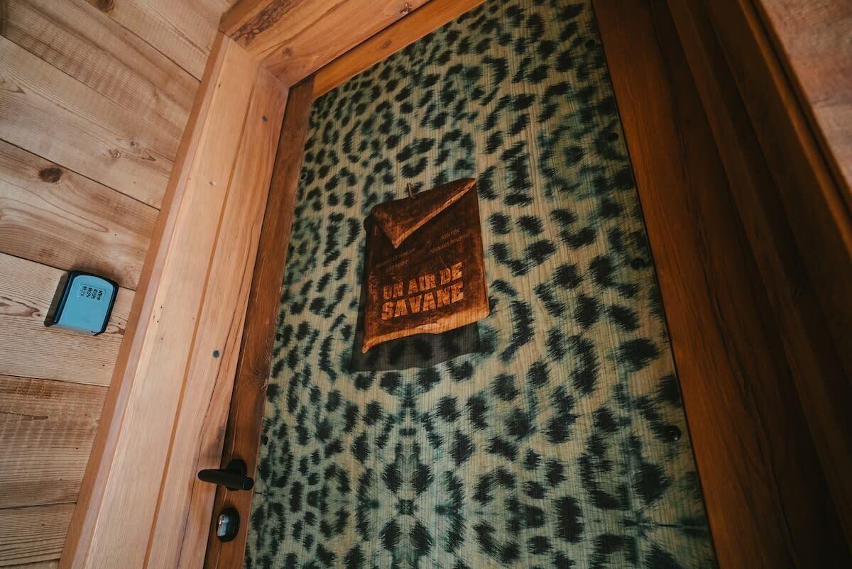 Una porta di legno con tessuto a stampa leopardo e un cartello con la scritta "UN AILE DE SAVANE".