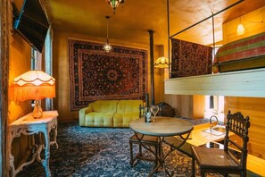 A cozy room with a yellow sofa, a round wooden table, and a patterned rug.
