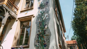 Un immeuble doté d’un balcon, de grandes fenêtres et d’une fresque florale sur le mur.