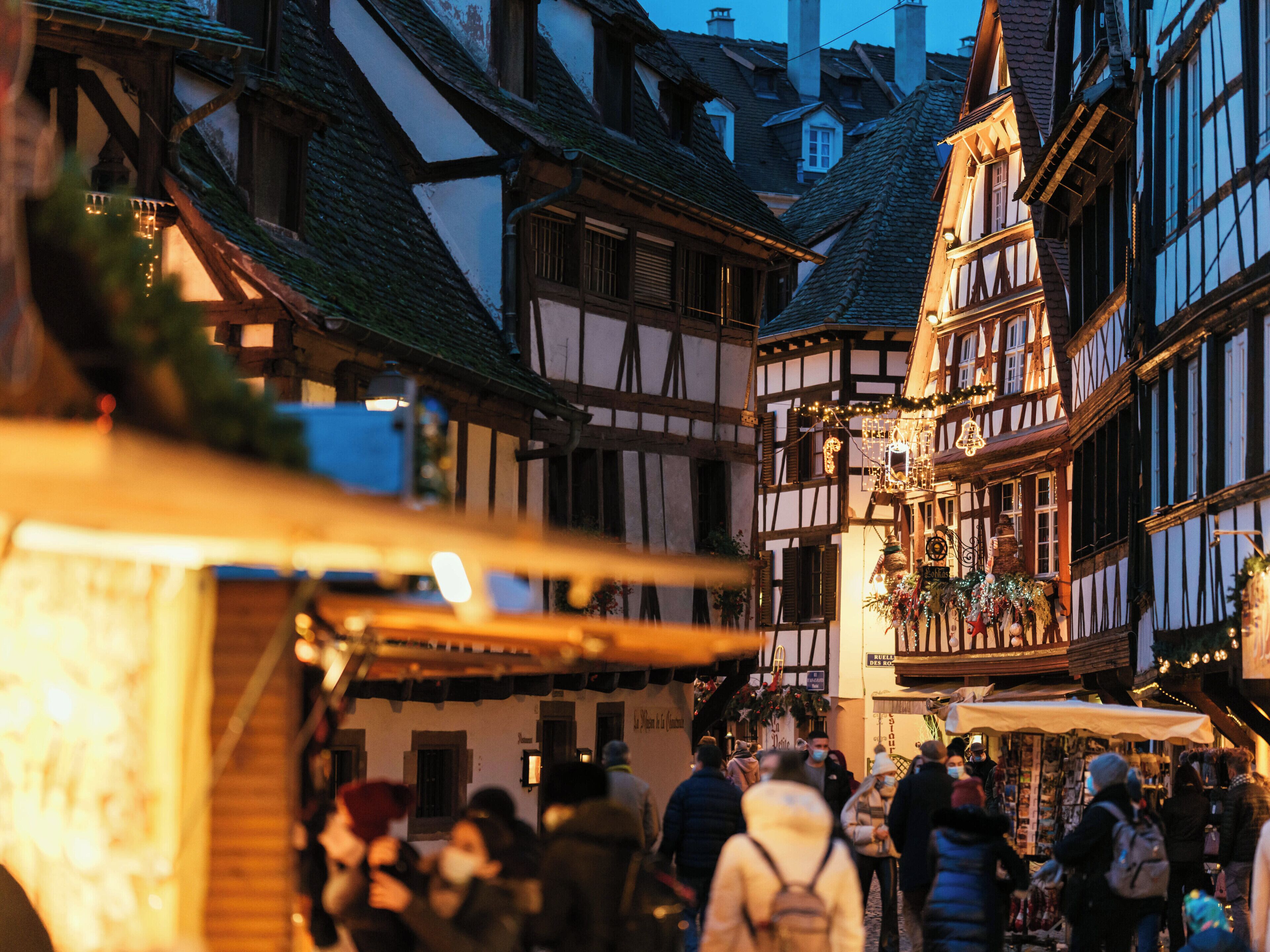 A traditional European market street with half-timbered buildings and a crowd of people.