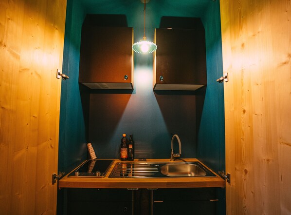 A kitchen with wooden cabinets, a stainless steel sink, and a hanging light fixture. - Viva Frida ! Unique accommodation with private jacuzzi in Alsace (Guebwiller)