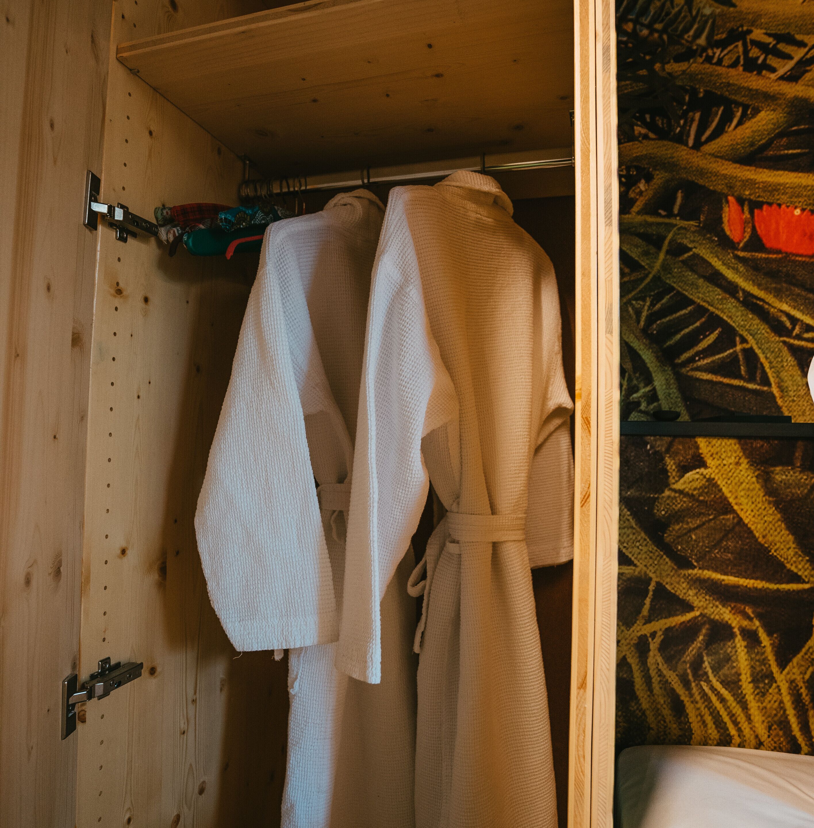 A wooden wardrobe with a hanging rod and a metal clasp.
