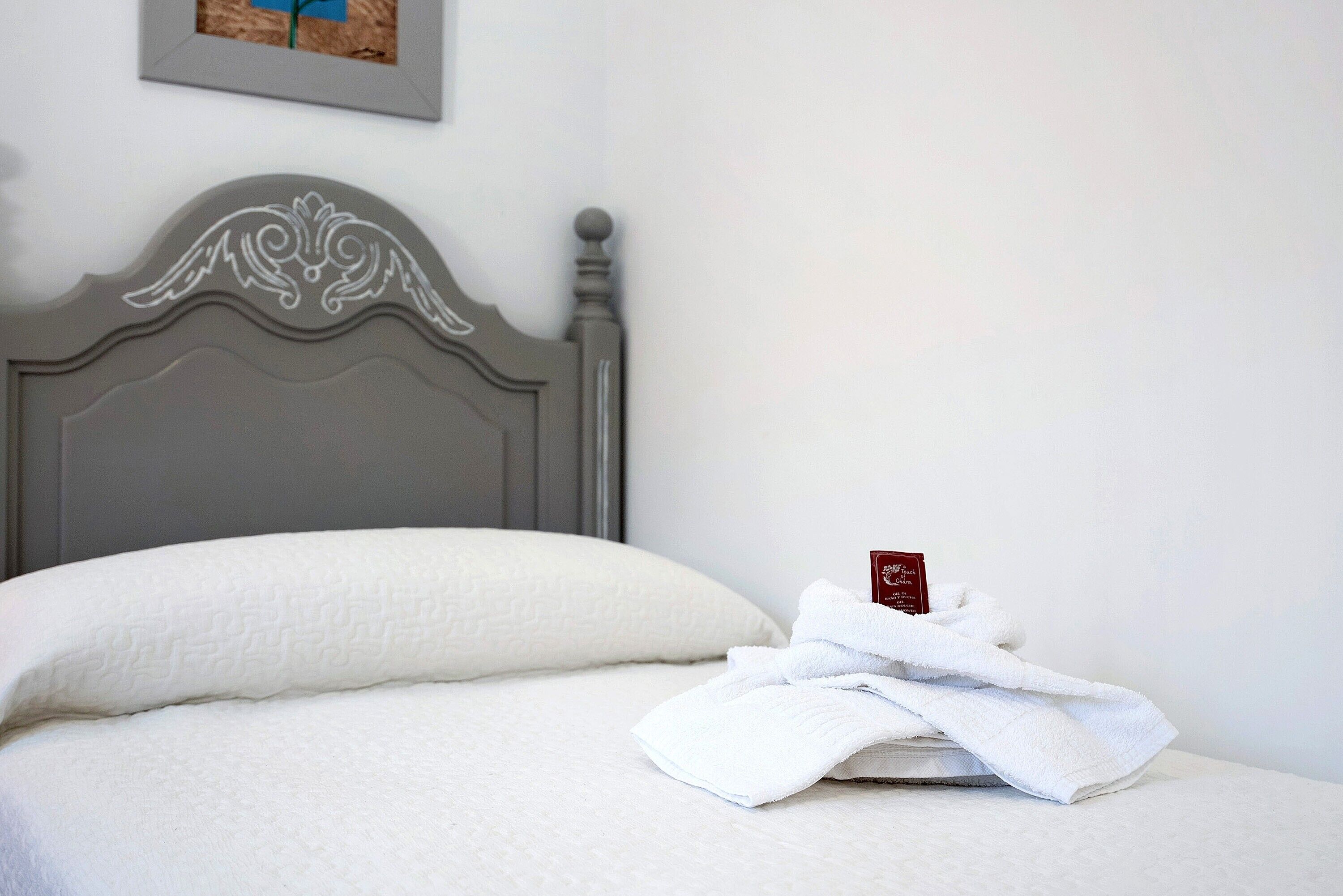 Una cama bien hecha con una almohada y una toalla doblada encima.